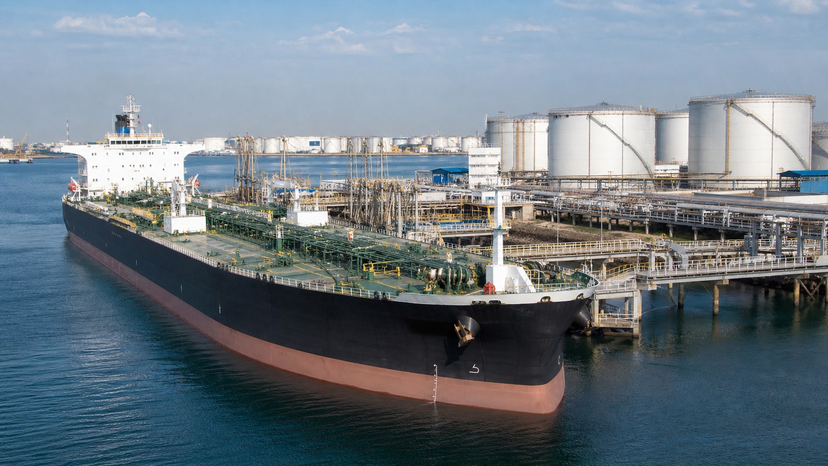 Petroleum tanker berthed beside terminal loading and storage infrastructure